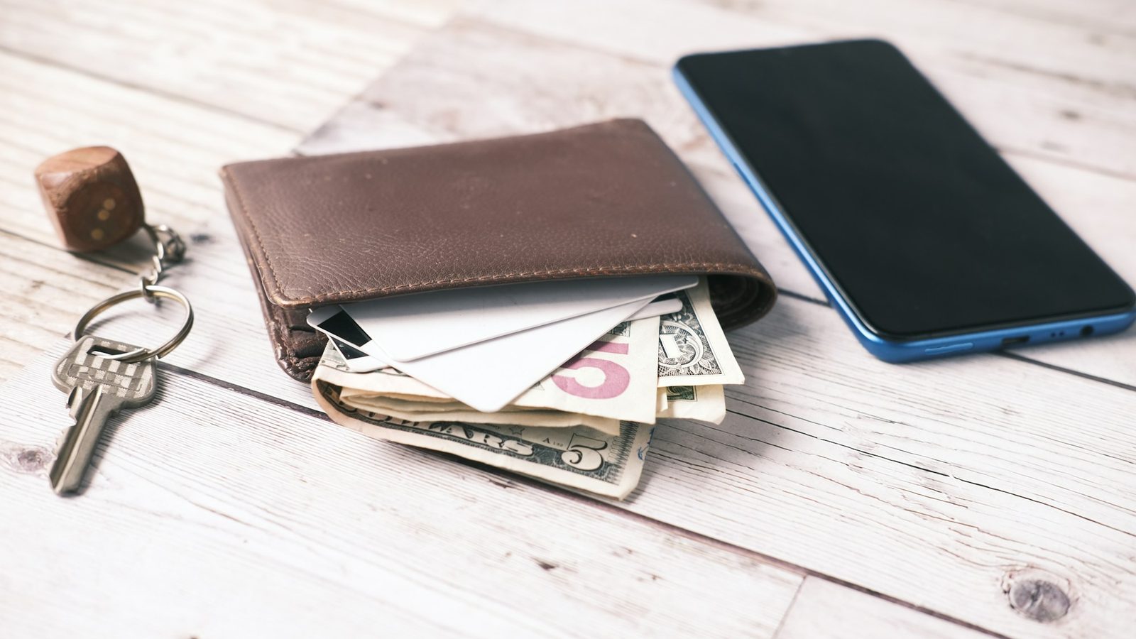 A wallet, a phone and keys on a table